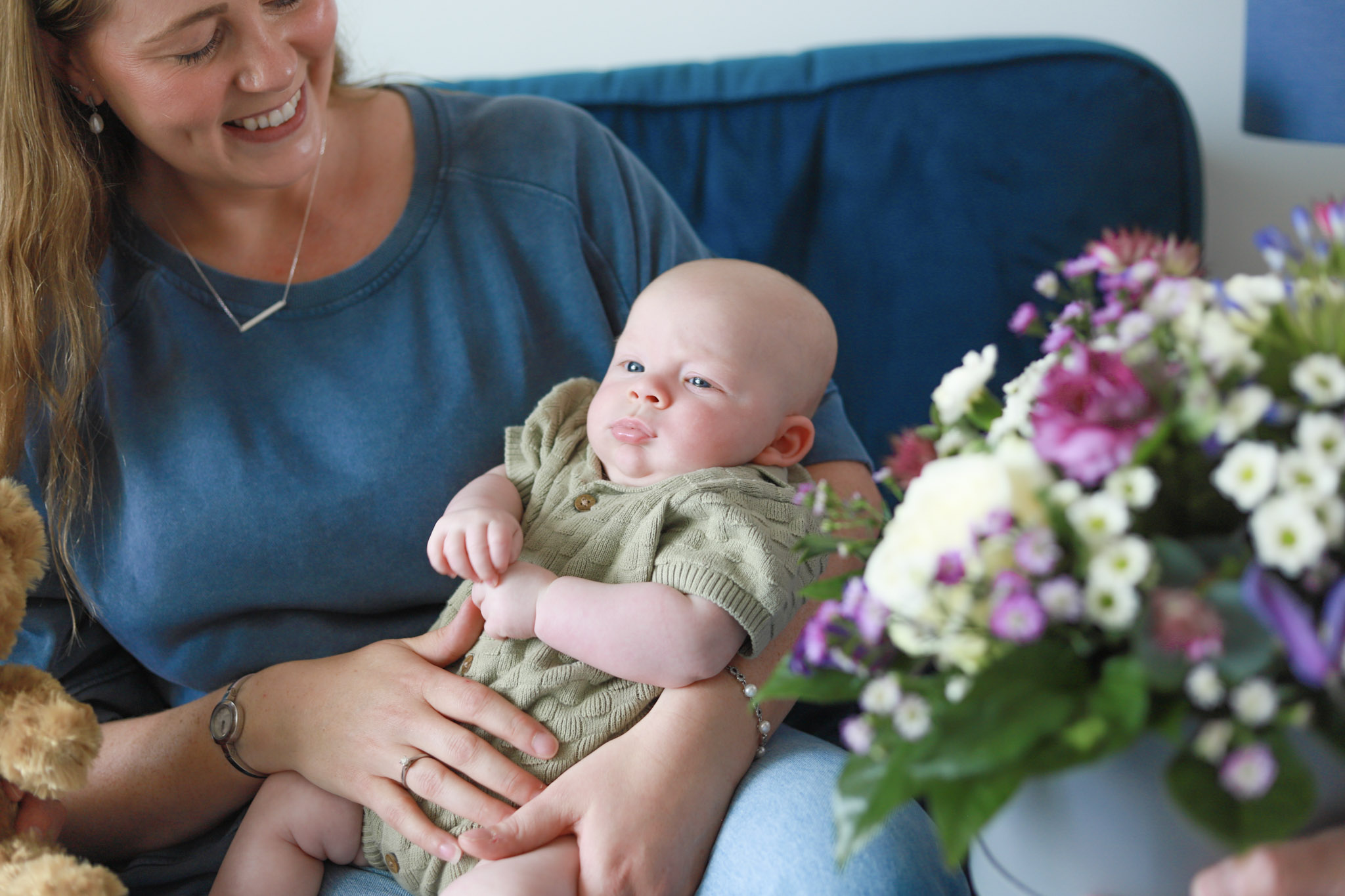 Mum holding newborn baby with same day flower delivery in foreground from local florist